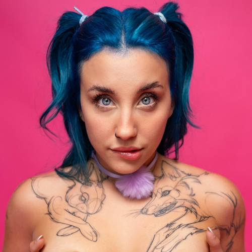 A model on OnlyFans free with bright blue hair styled in pigtails poses against a pink background, highlighting her playful expression and unique animal-themed chest tattoos.